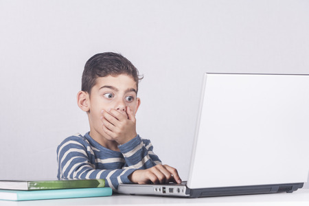 Young boy reacts while using a laptop. Internet safety for kids conceptの写真素材
