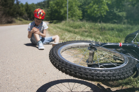 Boy is lying hurt after a bicycle accident. Kids safety concept. Selective focus toned image with...