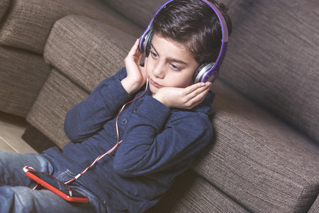 Boy listening to music using his smartphone and a set of headphonesの写真素材