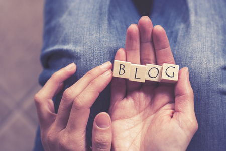 Hands holding Blog message formed with wooden blocks. Cross processed image with shallow depth of fieldの写真素材