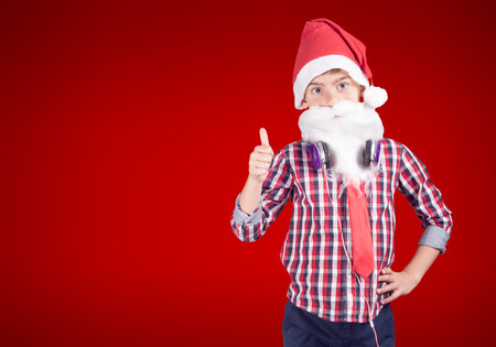 Confident little boy dressed up as Santa Claus poses with a set of headphonesの写真素材