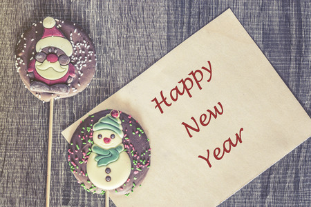 Christmas card with Happy New Year message and chocolate figures on a wooden backgroundの写真素材