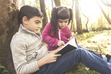 Children reading a book outdoors. Learning and education conceptの写真素材