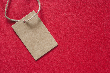 Blank tag made of recycled paper on red background