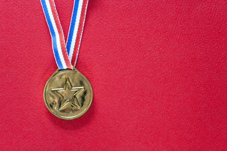 Gold medal on a red background. Winning and achievement conceptの写真素材