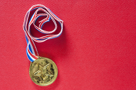Gold medal on a red background. Winning and achievement conceptの写真素材