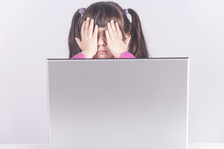 Little girl reacts while using a laptop. Internet safety and parental control conceptの写真素材