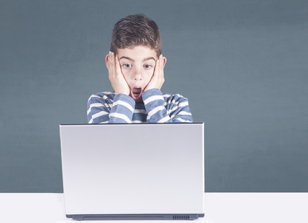 Young boy reacts after watching inappropriate content while surfing the internet. Internet safety and parental control conceptの写真素材