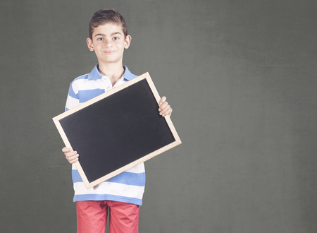 Boy holding a blank chalkboard with copy spaceの写真素材
