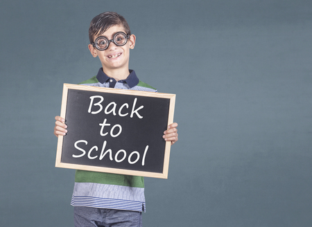 Funny nerd kid holding a blackboard with back to school messageの写真素材
