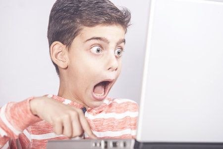 Little boy reacts after accidentally watching inappropriate content while surfing the internet. Internet safety and parental control conceptの写真素材