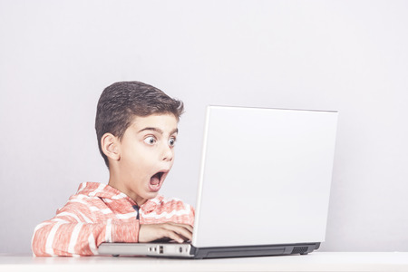 Little boy reacts after accidentally watching inappropriate content while surfing the internet. Internet safety and parental control conceptの写真素材