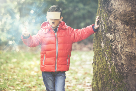 Little boy reacts while experiencing virtual reality outdoorsの写真素材