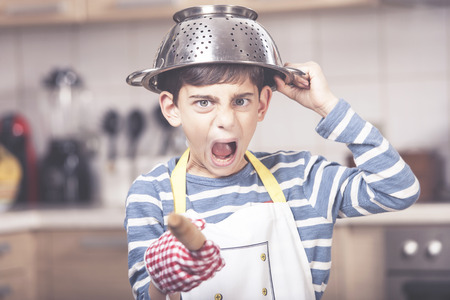 Funny angry boy chef shouting in the kitchenの写真素材