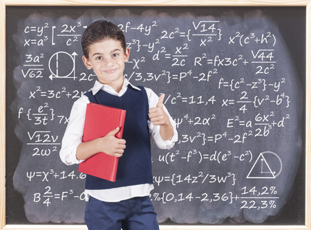 Education concept with confident school boy in front of a blackboardの写真素材