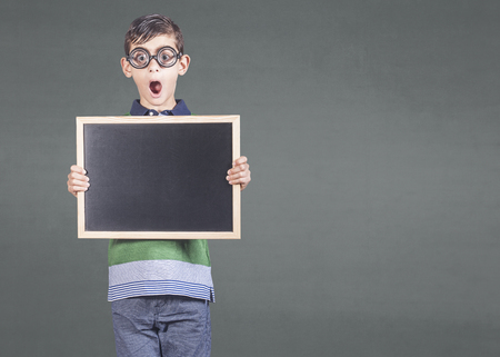 Funny little geek boy holding a blackboard with copy spaceの写真素材