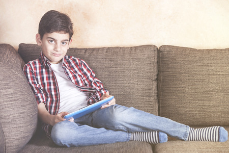 Young boy using his tablet at home. Kids and technology conceptの写真素材