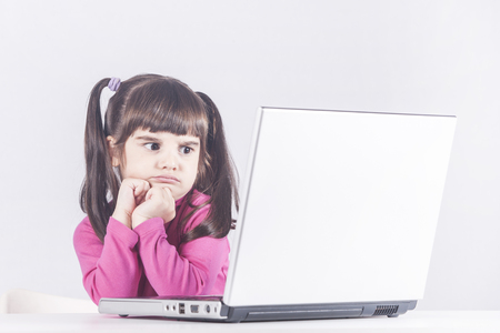 Little girl reacts while using a laptop. Internet safety and parental control conceptの写真素材