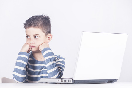 Sad little boy in front of a computer. Cyber bullying concept