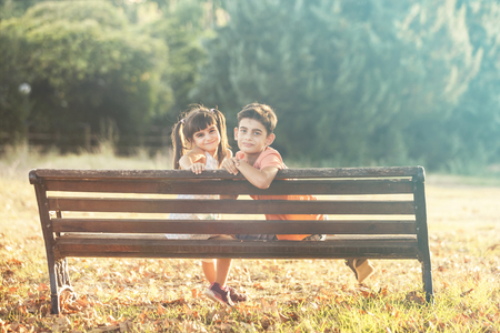 Kids sitting on a bench in autumn park. Innocent childhood conceptの写真素材