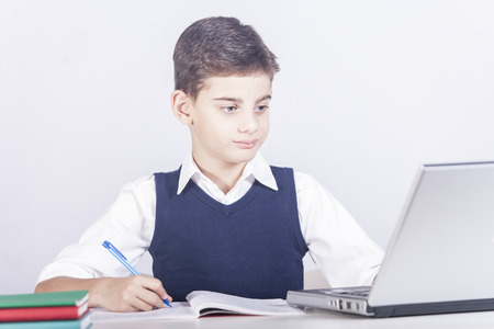 Young boy doing his homework using a laptop computer. E learning conceptの写真素材