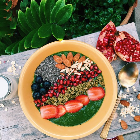 Spinach banana green smoothie bowl, topped with almonds, granola and fresh fruitsの写真素材