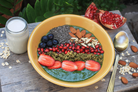 Breakfast green smoothie bowl, topped with almonds, granola and fresh fruitsの写真素材