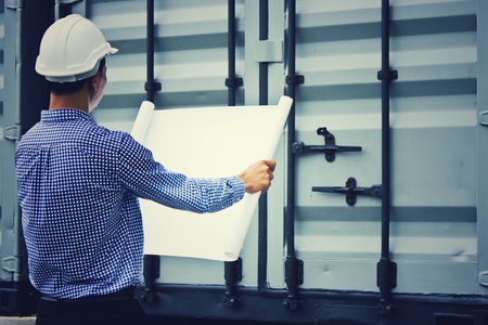 Asian engineer who hold the blueprint was standing on site with grey container backgroundの写真素材