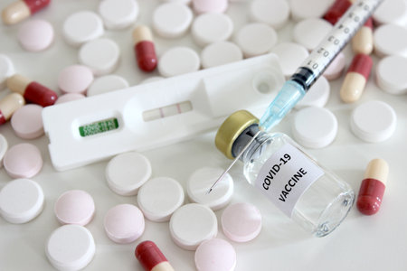 Vial of Covid-19 vaccine, 1 ml plastic syringe with needle, positive test result of Covid-19 antigen...