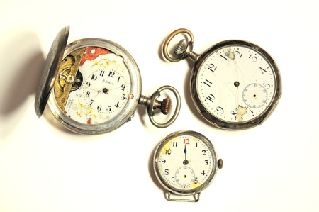 Old and damaged silver pocket watches on white.