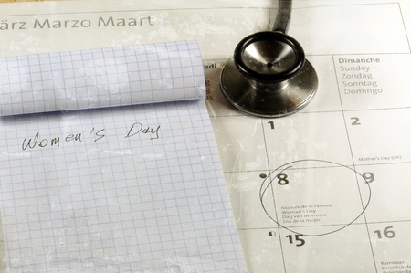 Desk with stethoscope, calendar and notebook. Women's day concept.の写真素材