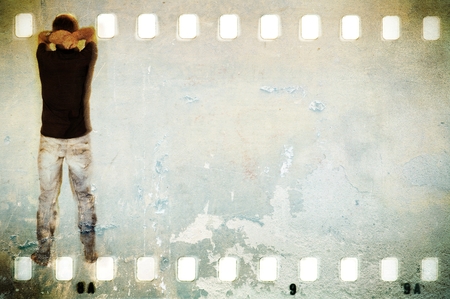 Debacked wall in film strip frame with unrecognizable  figure of young man and blue jeans.の写真素材