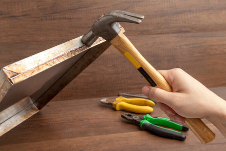 Man handle hammer to hit or fix stainless tray on wooden background.の写真素材