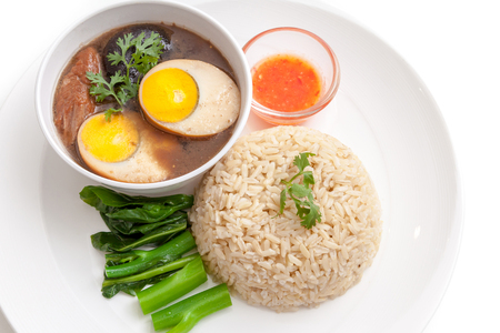 Eggs and pork in brown sauce served with brown rice, vegetable and chili sauceの写真素材