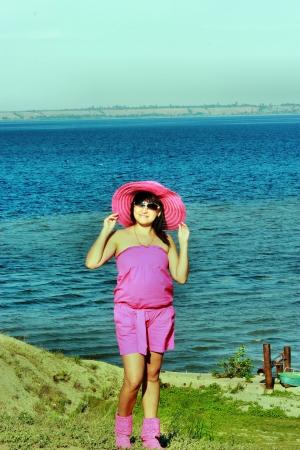 Beautiful young brunette woman standing on the beachの写真素材