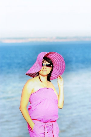 A girl in a hat and a suit is against the backdrop of the seaの写真素材