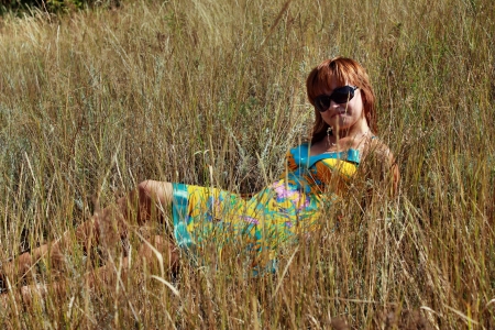 Girl in sunglasses lying on the grassの写真素材