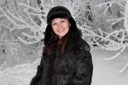 Beautiful girl stands near the snow-covered treeの写真素材