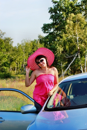 The girl in the pink hat near a car in a forestの写真素材