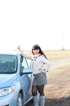 Happy brunette in front of his car with the keys in handの写真素材