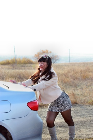 Brunette in autumn forest pushes carの写真素材