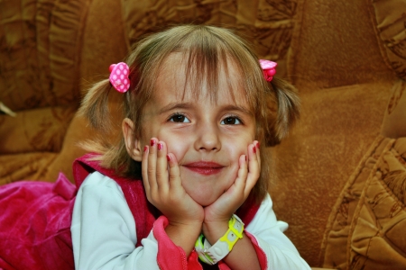 Little smiling girl lying on the sofaの写真素材