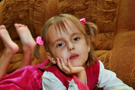 Serious girl leaning podborodog hand, lying on the sofaの写真素材