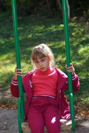 The girl on the playground in a tracksuit on a swingの写真素材