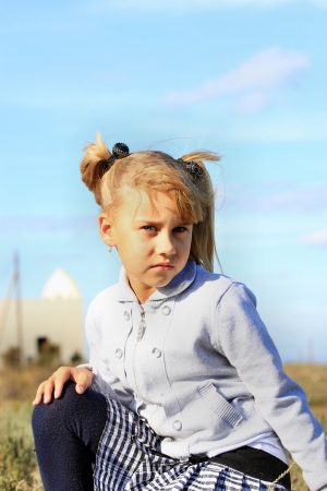 Beautiful girl sitting on the grass against the blue skyの写真素材