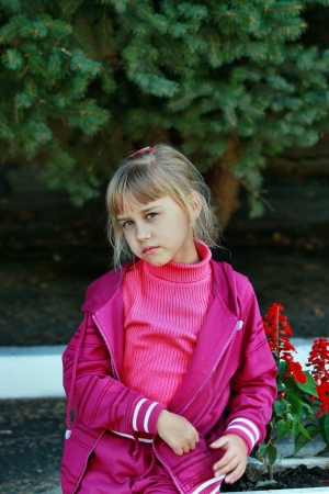 Sad girl in a sports suit standing near the spruceの写真素材