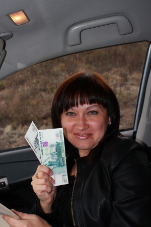 Happy girl in the car with the money in the hands ofの写真素材