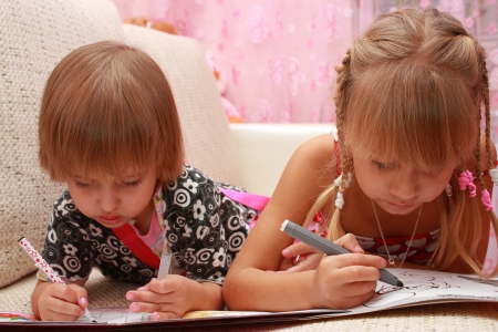 Girls with paint pens drawing lying on the couchの写真素材