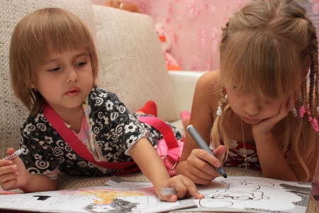 Sisters together paint coloring, lying on the couchの写真素材