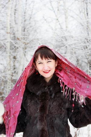 A young girl in a pink scarf in the winter woodsの写真素材